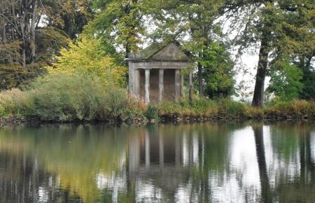 Small Classical temple on edge of lake surrounded by trees 