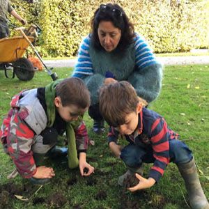 Schoolchildren undertake activities in a garden supervised by an adult.