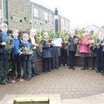 Schoolchildren hold Christmas wreaths of leaves and pine-cones they have made.